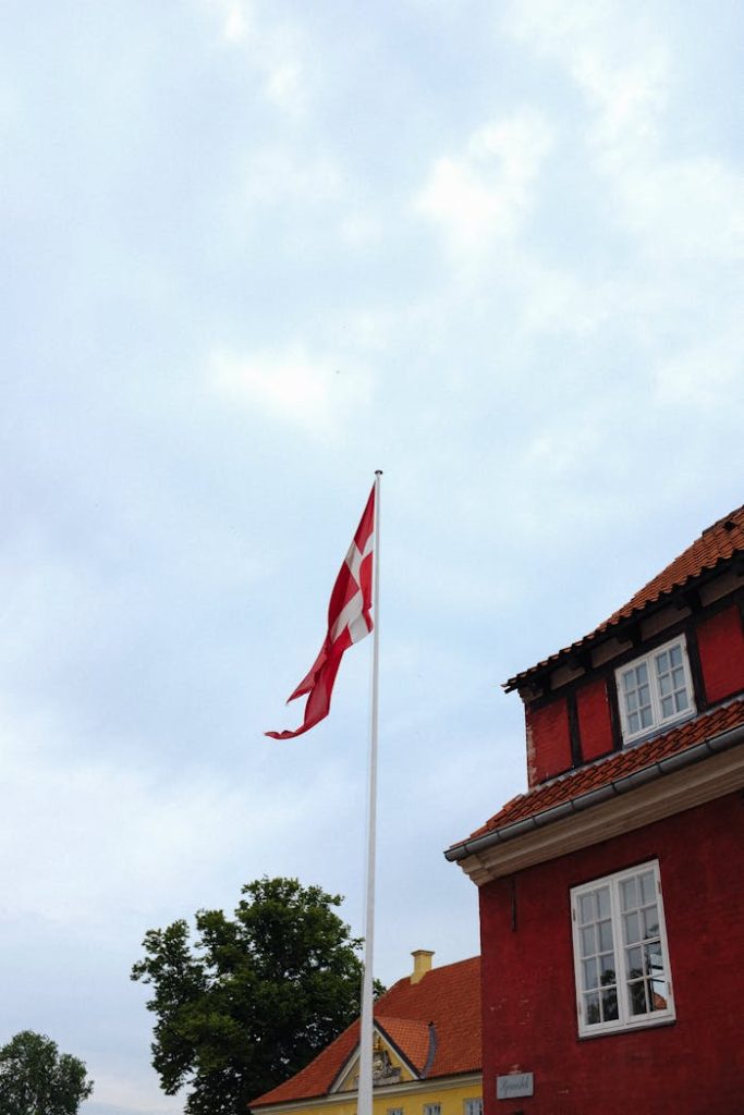 The Flag of Denmark Waving under a Cloudy Sky